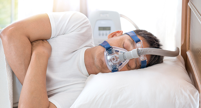 Hombre dormido con un CPAP (tratamiento para la apnea del sueño).